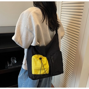 Dettaglio della borsa hobo a tracolla con tasca gialla a coulisse e tessuto in nylon nero