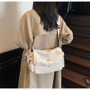 Close-up of cream nylon crossbody bag featuring YOU JI BEAR logo and textured finish