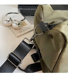 Detail of olive green nylon bag showing silver hardware hooks and adjustable black strap