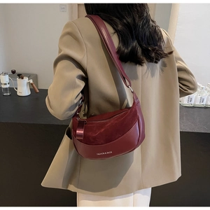 Detail of burgundy matte saddle bag featuring suede patchwork and adjustable shoulder strap