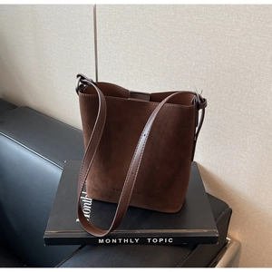 Close-up of brown suede bucket bag with adjustable strap and fashion bags engraving
