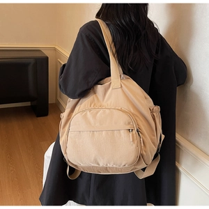 Detail of beige waterproof nylon tote bag with large front pocket and side elastic pouches