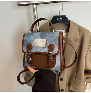 Close-up of vintage denim tote bag with brown leather trim and silver metal buckle details