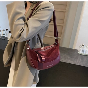 Detail of red crescent shoulder bag featuring premium matte texture and wide strap design