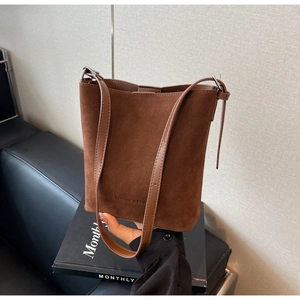 Detail of dark brown matte bucket bag showing the fashion logo and adjustable strap