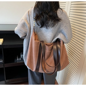 Large terracotta canvas tote bag with brown leather handles worn by model in casual setting