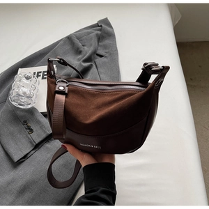 Detail view of brown half-moon saddle bag showing matte leather texture and metal zipper