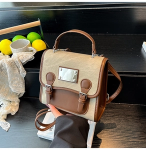 Close-up of vintage beige canvas handbag with brown leather trim and metal clasp detail