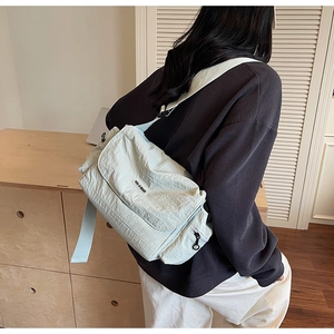 Close-up of mint green nylon crossbody bag with YOU JI BEAR logo on casual model