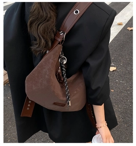 Close-up of brown vintage hobo bag featuring matte leather texture and a braided rope charm