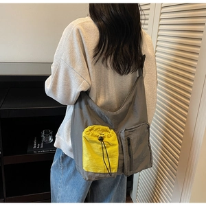 Dettaglio della borsa a tracolla grigia con tasche gialle a coulisse e nylon resistente