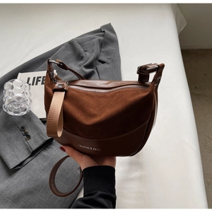 Detail of a brown vintage saddle bag with mixed textures and FASHION & BAGS lettering