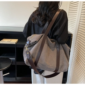 Macro view of dark grey canvas tote with brown leather strap and side pocket details