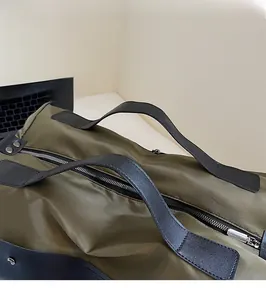 Detail of army green canvas travel bag showing ergonomic handles and metal hardware