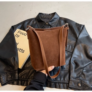 Detail of dark brown suede bucket bag with embossed logo and smooth leather strap