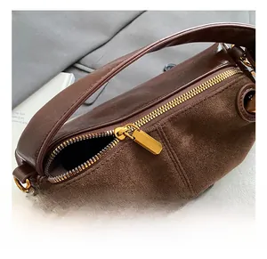 Close-up of golden zipper detail on dark brown leather and suede stitching bag