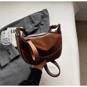 Detail of vintage brown suede leather saddle bag with wide strap and silver metal zipper