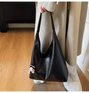 Detail showing the lychee grain texture of the large black tote bag with a white dog charm