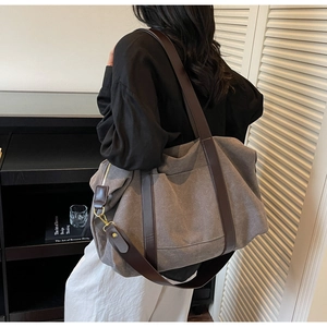 Detail showing grey canvas tote bag with brown straps and metal zipper pocket