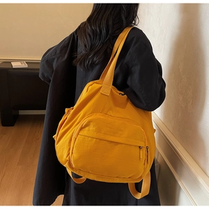 Detail of a bright yellow nylon tote backpack with large zipper pockets for commuting