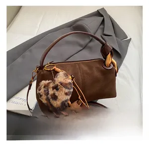 Macro shot of dark brown frosted leather texture and leopard print heart charm on bag