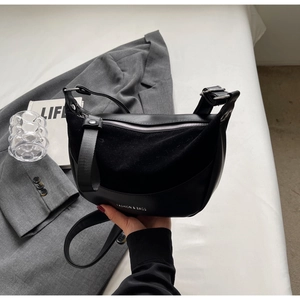 Detail of minimalist black saddle bag with FASHION & BAGS text and matte leather texture