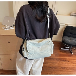 Detail view of mint green nylon messenger bag with adjustable strap in a lifestyle setting