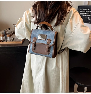 Detail of a vintage denim mini backpack with brown leather trim and metal buckles