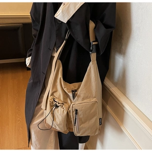 Dettaglio della borsa a tracolla in tela kaki con design multi-tasche e tracolla