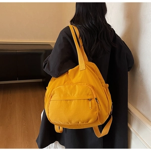 Rear view of a model wearing a large bright yellow nylon tote bag with drawstring pockets
