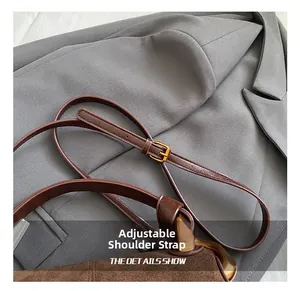 Detail of the adjustable brown leather strap with a gold-tone buckle on a shoulder bag