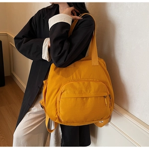 Detail of a bright yellow nylon tote bag with large zipper pocket and drawstrings