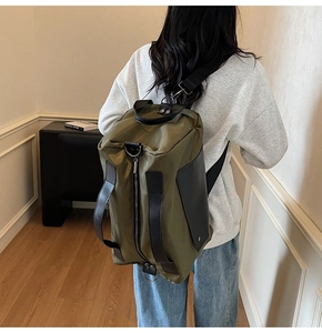 Olive green travel backpack with side handles and leather details worn by a person