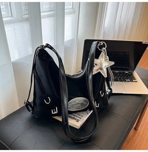 Detail of black functional tote bag featuring silver star pendant and metallic buckle accents