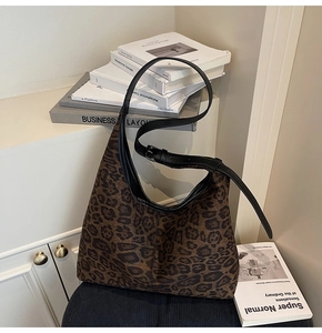 Close-up of leopard print tote bag with black leather strap and metal buckle detail
