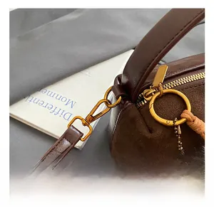 Detail of dark brown suede handbag with golden hardware and leopard fur ball charm