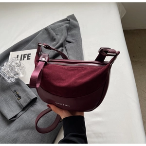 Detail of burgundy leather saddle bag with silver zipper and white text branding