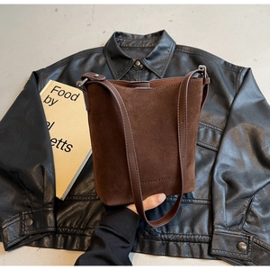Close-up of brown matte suede bucket bag texture and debossed fashion slogan detail
