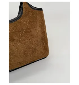 Vue détaillée de la texture matelassée en daim marron et bordure en cuir d'un sac seau