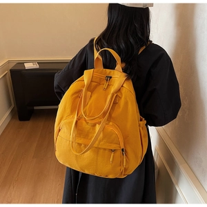 Back view of a large yellow nylon backpack worn by a model for commuting and school