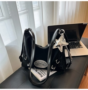 Close-up of black glossy shoulder bag with silver star charm and metal brand plate