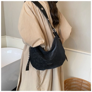 Detail of minimalist black hobo bag with large silver eyelets on a wide shoulder strap