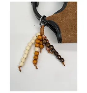 Détail d'un bijou de sac en perles de bois et cordon tressé sur un sac seau en daim