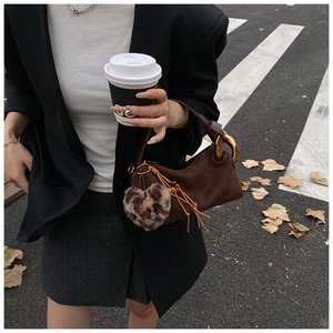 Retro brown suede handbag with leopard heart charm and tassel detail in street setting
