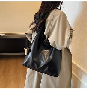 Detail of black large capacity tote bag with smooth texture and cute puppy charm