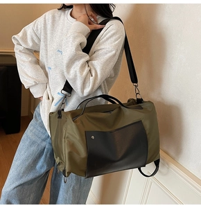 Detail of army green canvas travel bag with black leather pocket and metal buckle