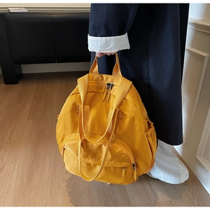 Detail of mustard yellow multi-pocket tote backpack with wide handles for versatile carrying