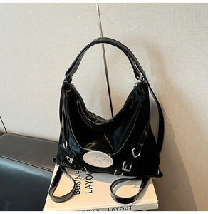 Detail of glossy black patent leather Hobo bag with silver buckles and metallic logo
