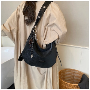 Detail of black leather hobo bag with silver eyelets and beaded charm accessories