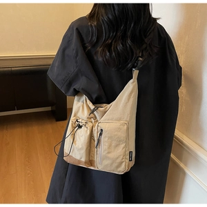 Dettaglio borsa a tracolla kaki con tasche multiple funzionali e design con coulisse